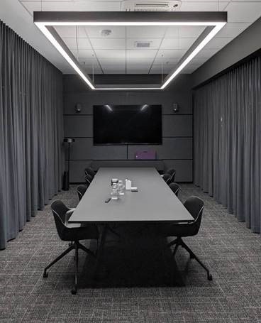 Ein Konferenzraum mit TV am Ende und einem langen Tisch mit Stühlen